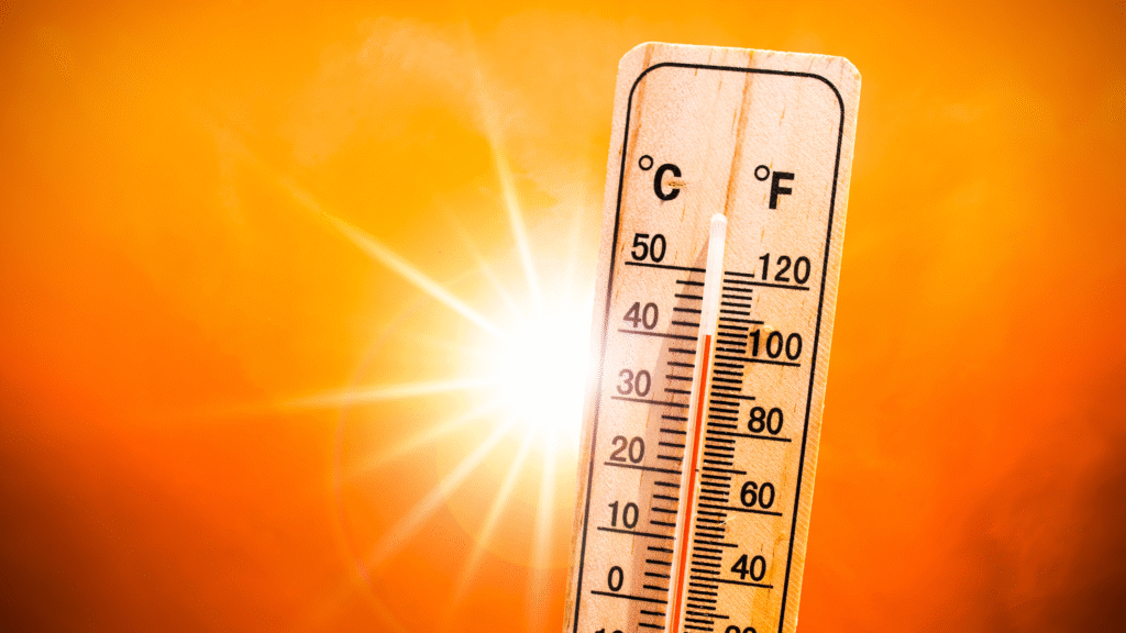Thermometer showing extreme heat with bright sun in the background.