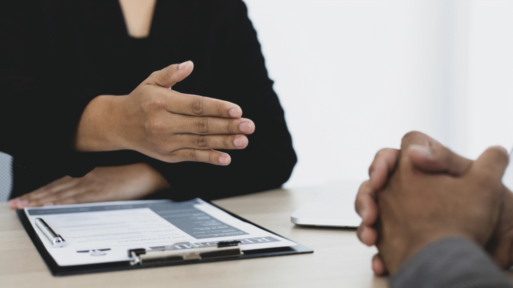 Close-up of a job interview with a hiring manager extending a hand for a handshake across a desk with a resume